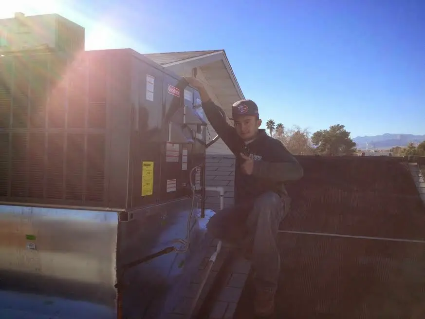 HVAC technician performing AC Tune-Up on a rooftop unit in Cheektowaga