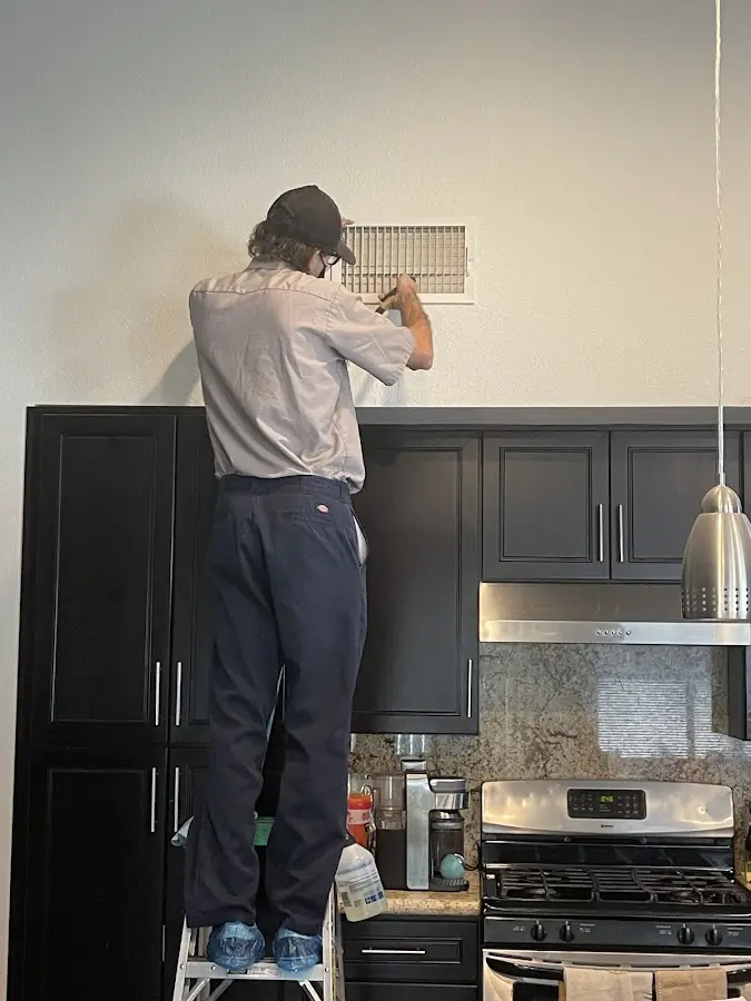 Technician inspecting an air vent during HVAC service in Cheektowaga